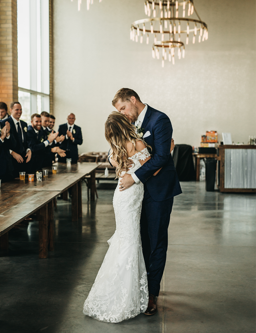 A couple's first dance in the event hall under a chandelier